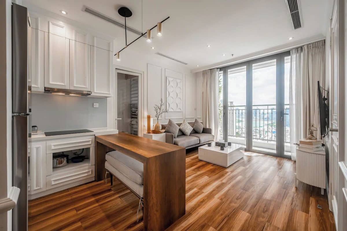 Eine moderne Küche mit weißen Schränken, einer Holzeinsele und einem großen Fenster mit Blick auf die Stadt.