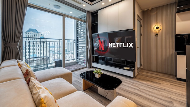 A modern living room with a large flat-screen TV, a sofa, a coffee table, and a view of a cityscape through a large window. - Landmark 81 & Vinhomes - ZEN Saigon Citypoint. (Ho Chi Minh City)