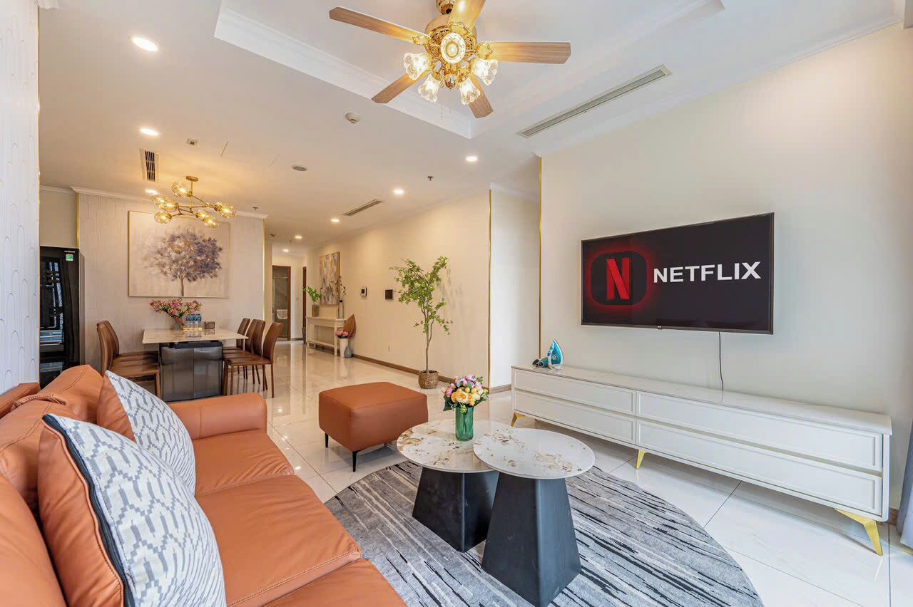 A modern living room with a leather sofa, a coffee table, and a TV mounted on the wall displaying the Netflix logo.