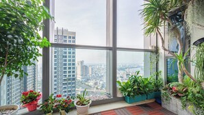 A balcony with large windows, potted plants, and a city view.