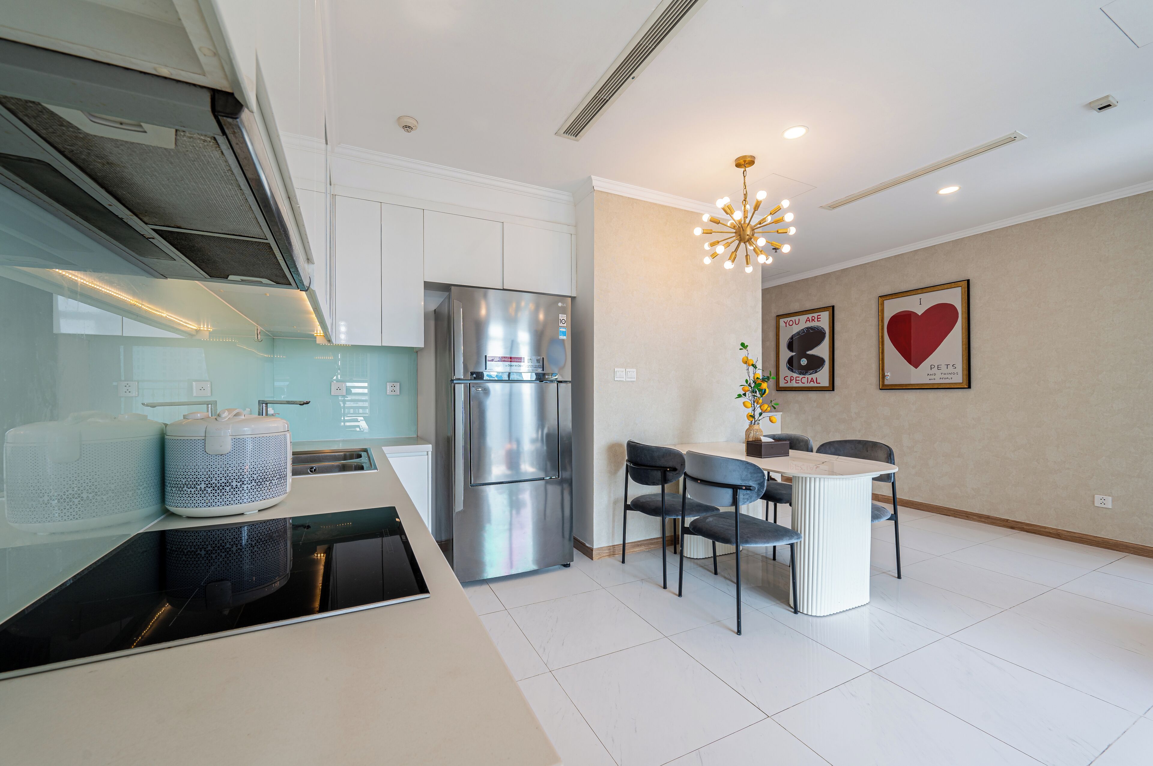 Een moderne keuken met een ingebouwde oven, een roestvrijstalen koelkast en een eethoek met een tafel en stoelen.