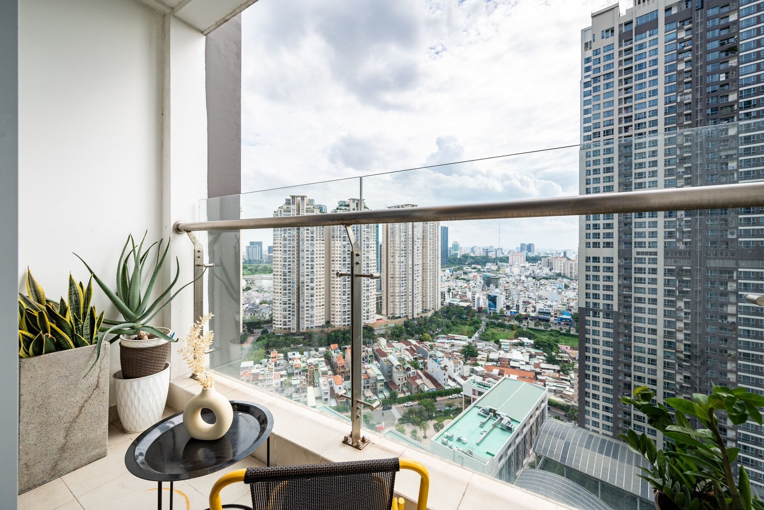 Un balcón con vistas a un paisaje urbano, con edificios altos y cielo despejado.