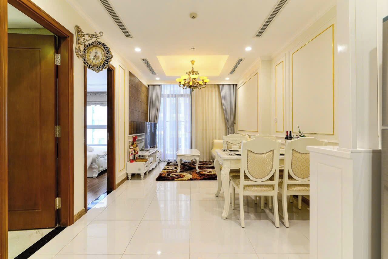 A spacious dining area with a chandelier, a television, and a dining table set for six.