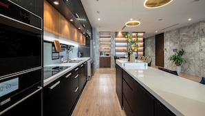 A modern kitchen with dark cabinetry, a white countertop, and a built-in oven. - Landmark 81 & Vinhomes - ZEN Saigon Citypoint. (Ho Chi Minh City)