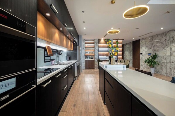 Eine moderne Küche mit dunklen Schränken, einer weißen Arbeitsplatte und einem eingebauten Backofen.