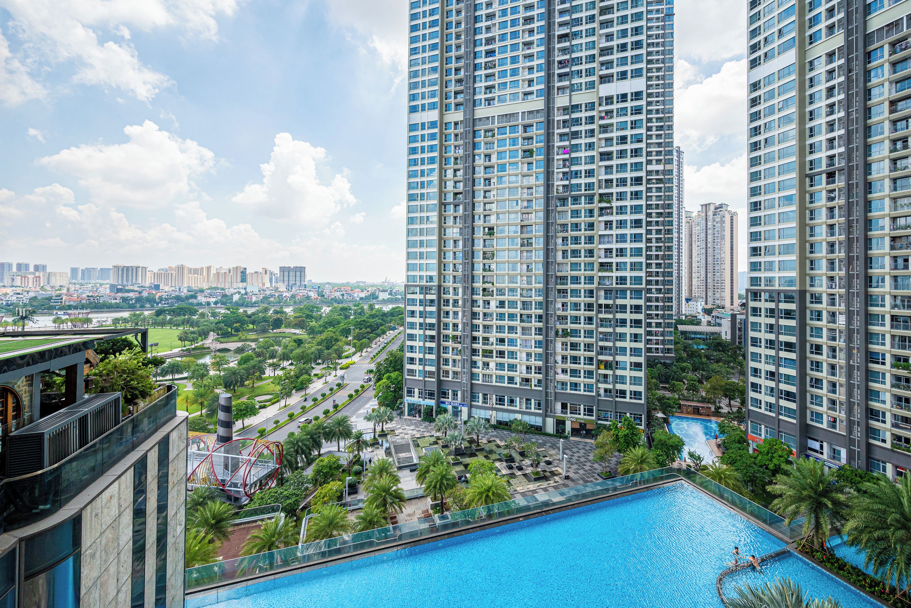 A high-rise building with a rooftop pool surrounded by greenery.