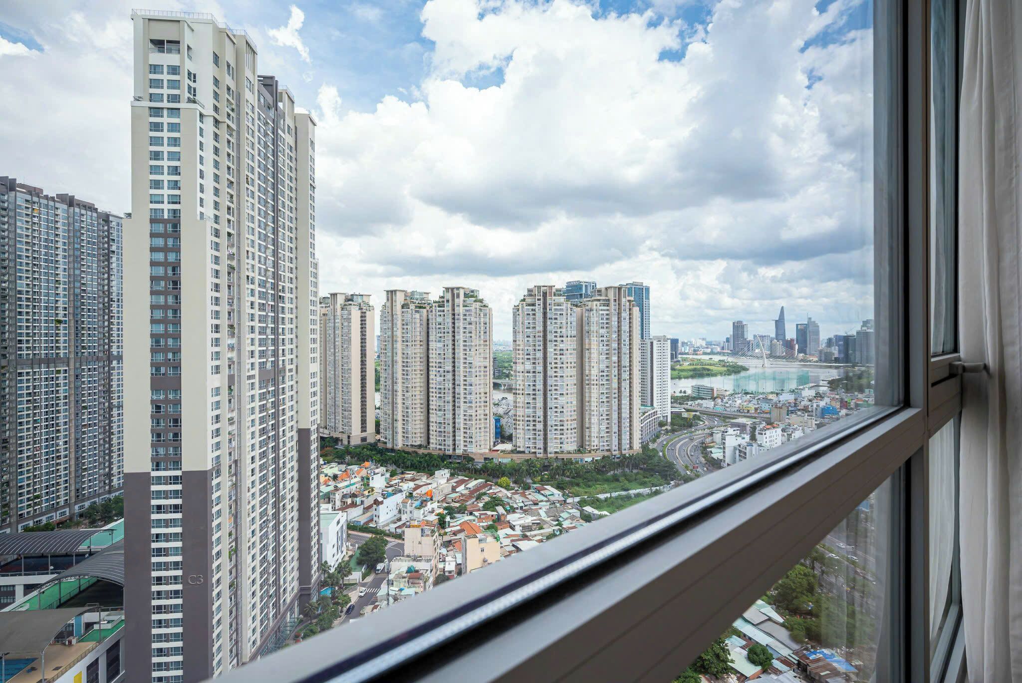 A high-rise building with multiple floors, large windows, and a view of a cityscape with other tall buildings and a river.
