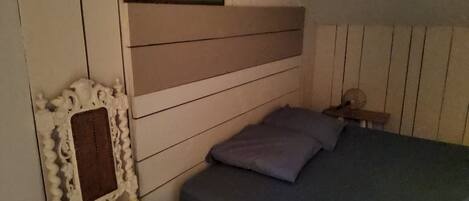 A bedroom with a bed, a chair, a nightstand, and a painting on the wall.