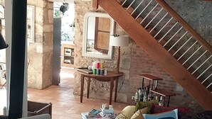 A spacious living area with a high ceiling, a staircase, and a view of the kitchen.