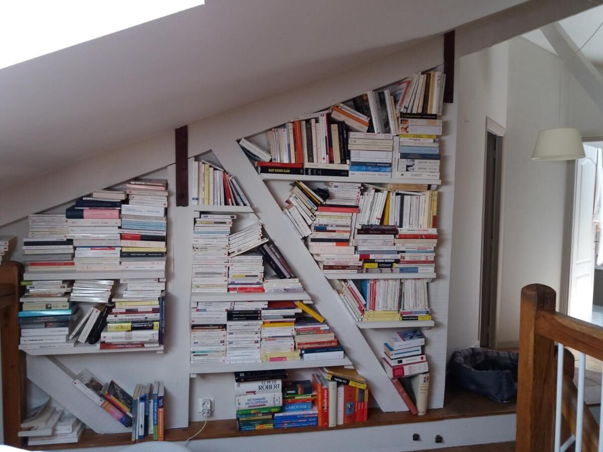 Een trap met boekenplanken aan weerszijden, die uitkomt op een plateau.