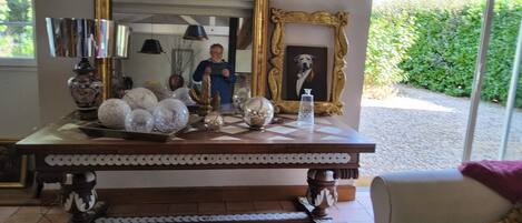 A room with a large mirror, a decorative table with various items, and a framed picture of a dog.