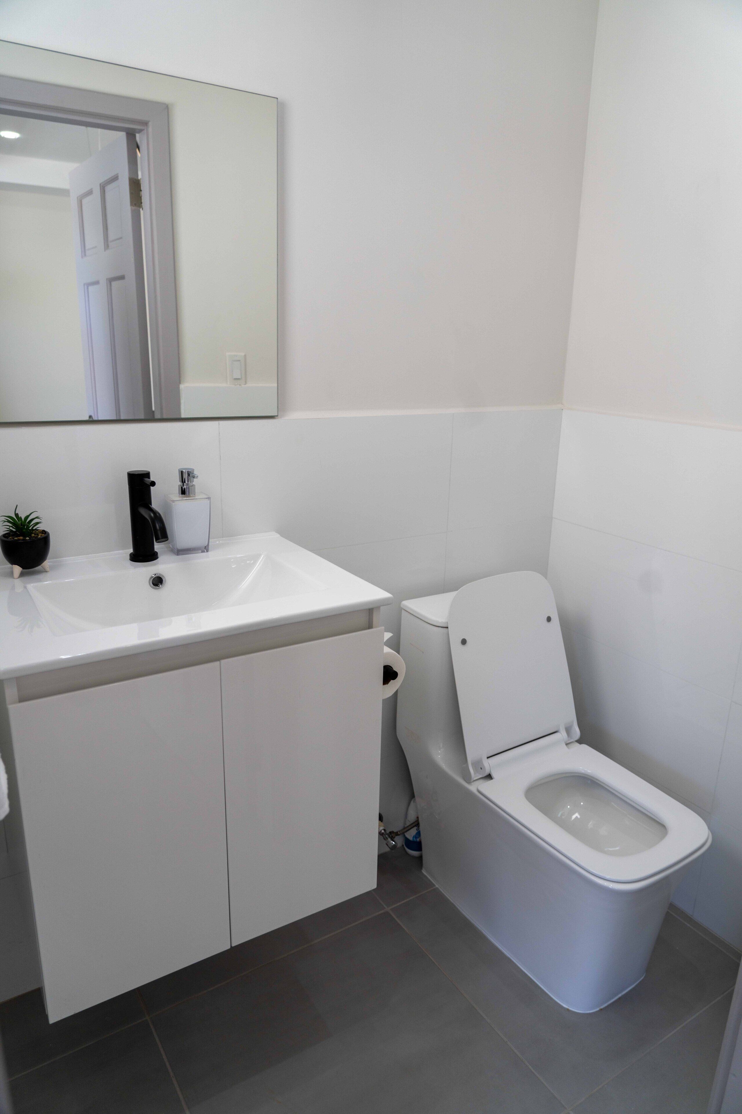 Un baño moderno con un lavamanos blanco, grifo negro y un inodoro.