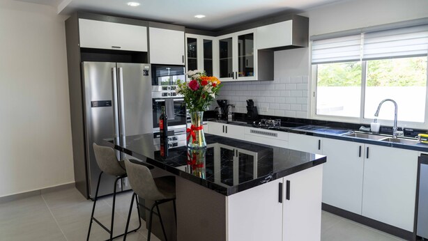 Una cocina moderna con una isla central, electrodomésticos de acero inoxidable y un ventanal que proporciona luz natural.