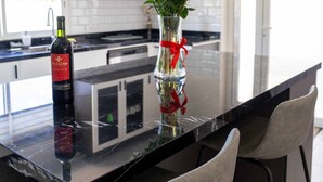 Una cocina moderna con encimera de mármol, una botella de vino y un florero con flores.
