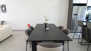 Una cocina moderna con una mesa de madera oscura, seis sillas y un refrigerador.