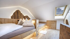 Een compacte slaapkamer met een houten stapelbed, een klein bureau en een wanddecoratie met bergmotieven.