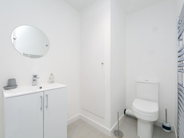 A modern bathroom with a white sink, mirror, and toilet. - Modern 2 bed Apartment in Rhosneigr - Pass the Keys (Rhosneigr)