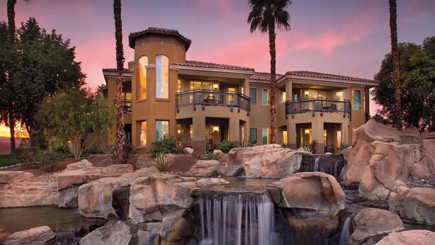 A resort with a waterfall, multiple balconies, and a sunset view.