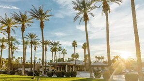 A hotel with a well-maintained lawn, palm trees, and a parking area.