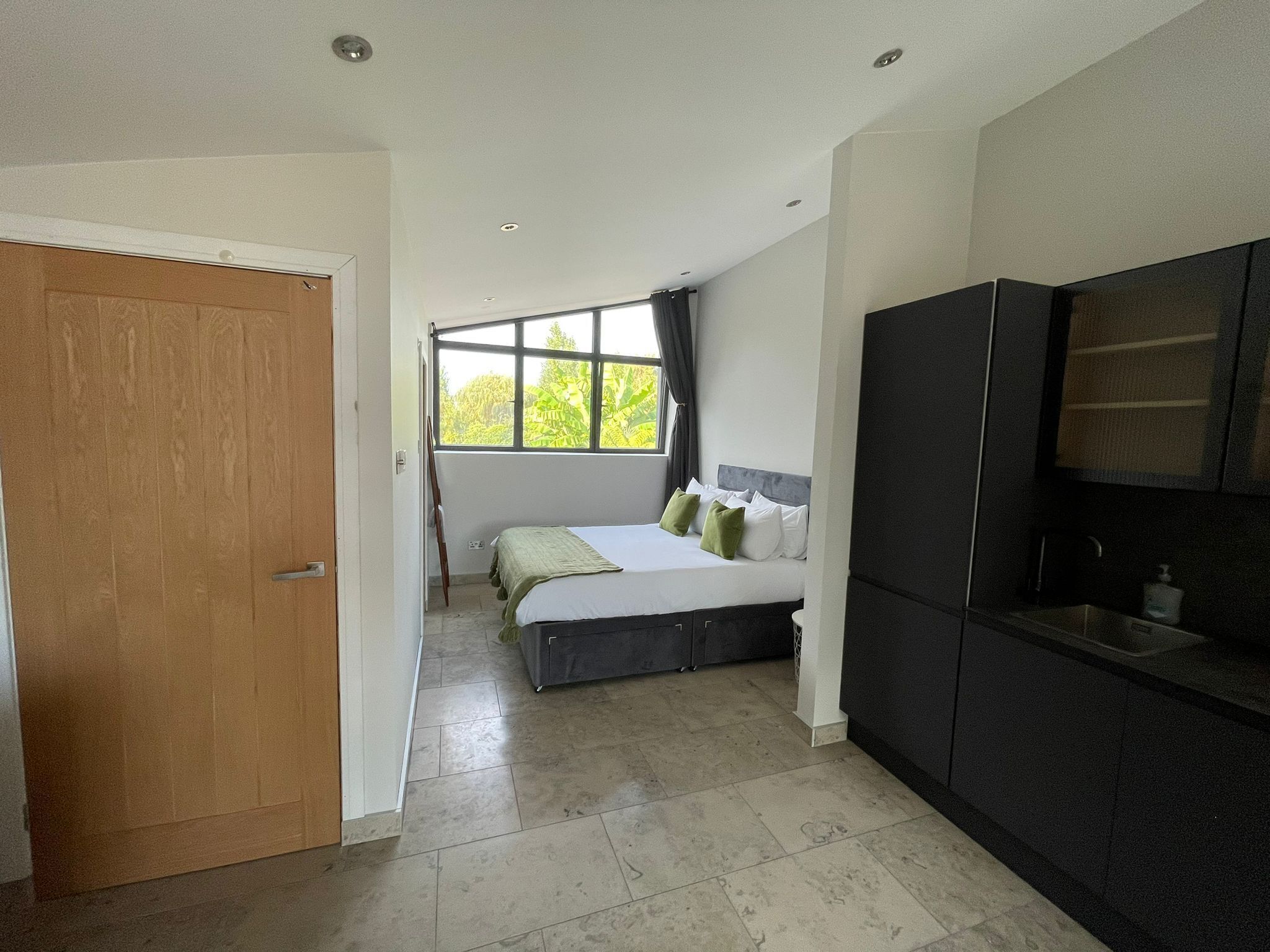 Un dormitorio con cama, ventana, armario y puerta.