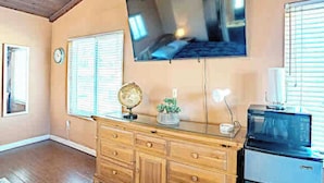 A room with a wooden dresser, a flat-screen TV mounted on the wall, a microwave, and a globe on the dresser. - Studio Suite with Private, Secured Entrance, No Shared Spaces, Driveway Parking  (Spring Valley)