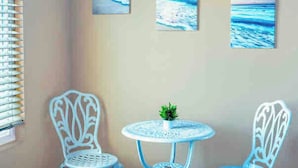 A room with three white chairs, a small round table with a plant, and three paintings of the ocean on the wall. - Studio Suite with Private, Secured Entrance, No Shared Spaces, Driveway Parking  (Spring Valley)