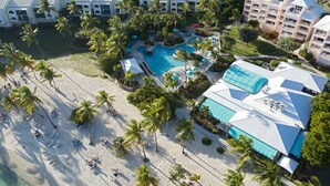 An aerial view of a resort with a central swimming pool, multiple buildings, and a beach area. - Oceanfront Cowpet Bay Condo Beach, Pool & Generator (St Thomas)