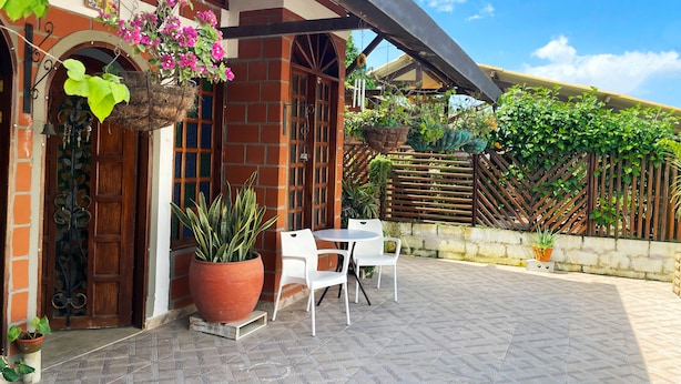 A patio with a brick wall, hanging plants, and a table with chairs.