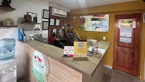 A hotel reception desk with a water dispenser, a framed certificate, and a calendar on the wall.
