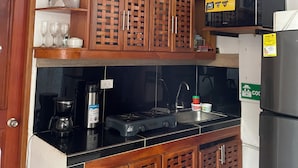 A kitchen with wooden cabinets, a black countertop, a microwave, a stove, and a refrigerator.