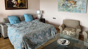 Hotellihuone, jossa on sänky, sohva, lasinen sohvapöytä, tuoli, taulu ja lamppu.