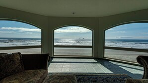 Quarto com vista para o oceano através de amplas janelas em arco, tapete estampado e um sofá.