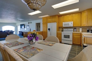 A modern kitchen with wooden cabinets, a white refrigerator, a microwave, and an oven. - Queen Bee - Beach Front w/ Vast Ocean Views, Spa (Gold Beach)