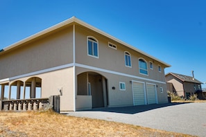 A two-story residential building with a garage, arched entryway, and a clear sky. - Queen Bee - Beach Front w/ Vast Ocean Views, Spa (Gold Beach)