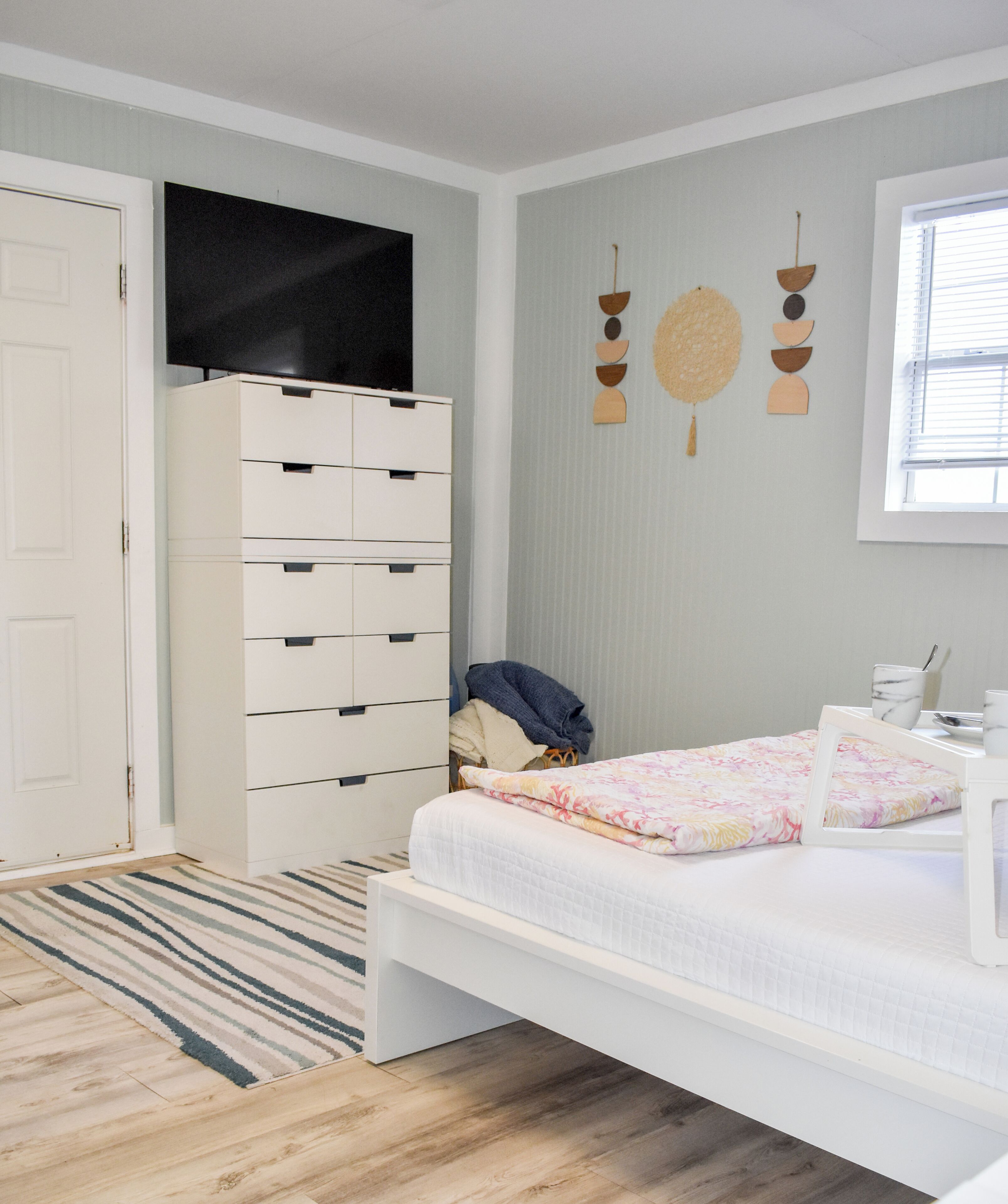 A bedroom with a bed, a wardrobe, a TV, and a window.