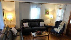 Un salon avec un canapé en cuir noir, une table basse en bois et un fauteuil bleu.