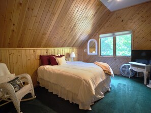 A bedroom with a bed, a chair, a television, and a window. - Peaceful, Woodland Retreat in Frankfort, MI Near Crystal Lake & Sleeping Bear (Frankfort)