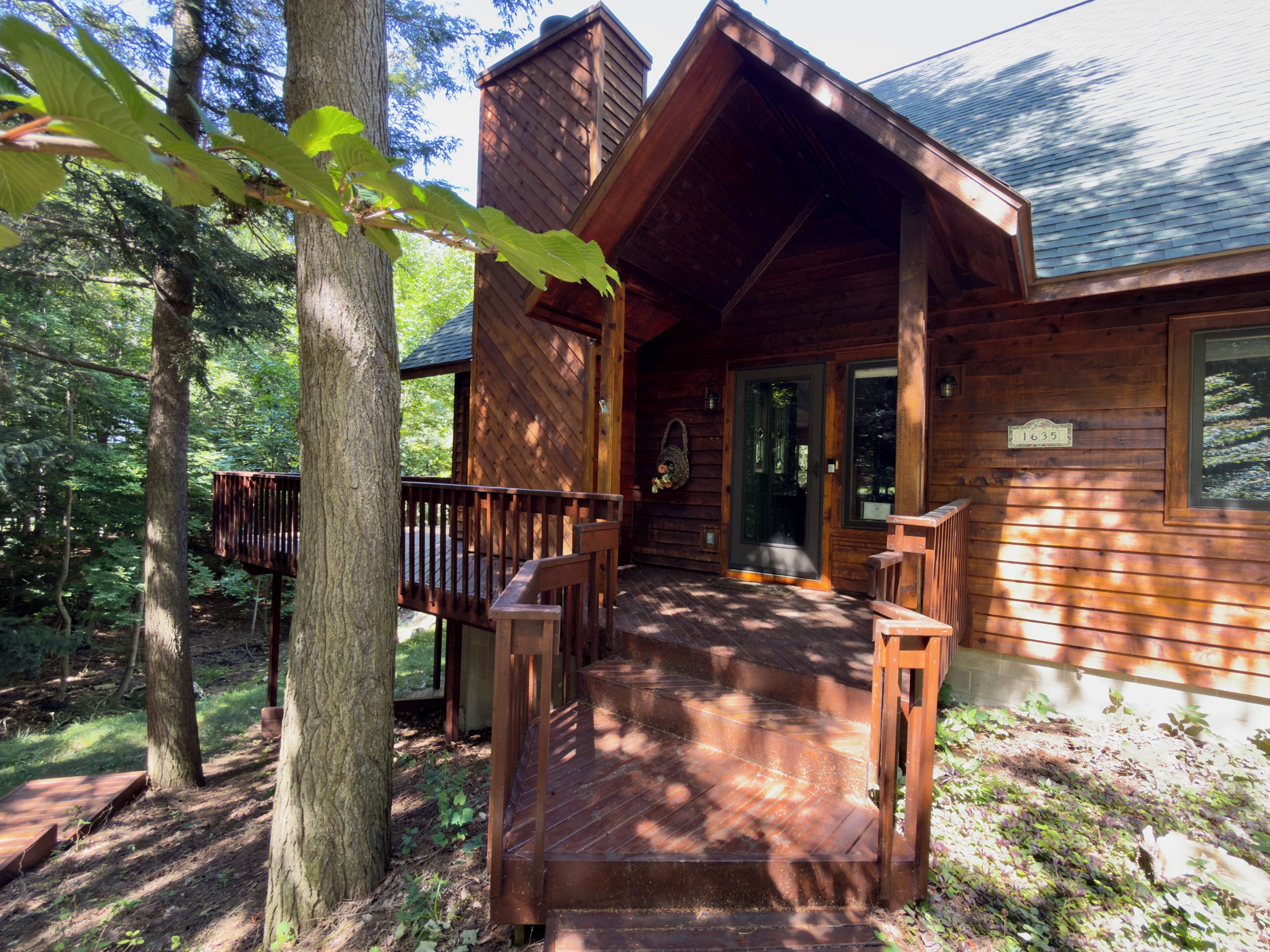 A wooden cabin with a porch, a door, and a window.
