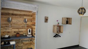 A room with a wooden wall unit, a hanging light fixture, and a small wooden shelf with a flower. - La Guitoune de Laroque (LAROQUE)