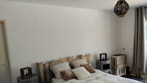 A bedroom with a wooden headboard, a bed with striped bedding, two bedside tables, and a hanging light fixture. - La Guitoune de Laroque (LAROQUE)