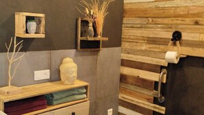 A modern bathroom with a wooden wall panel, a toilet, a sink with a wooden countertop, and a towel rack. - La Guitoune de Laroque (LAROQUE)