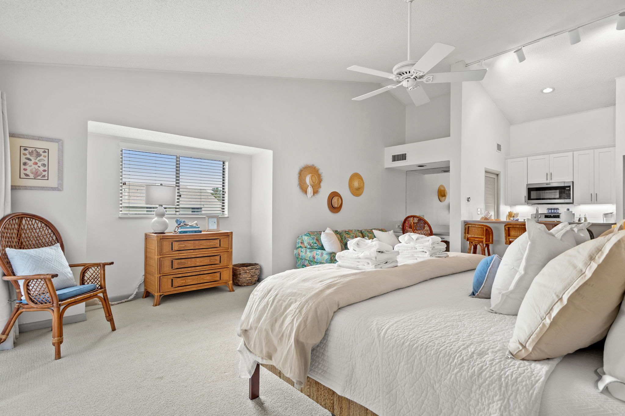 A bedroom with a bed, a dresser, a chair, a window with blinds, and a ceiling fan.