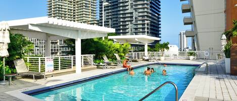 Una piscina con zona de borde, rodeada de edificios residenciales altos.