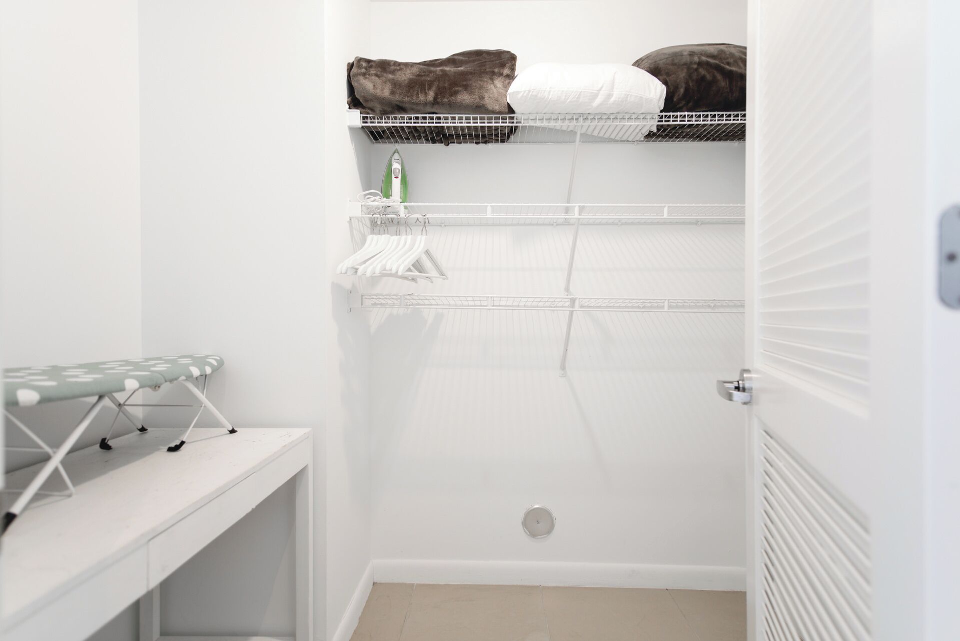 A small, white closet with a hanging rack and shelves.