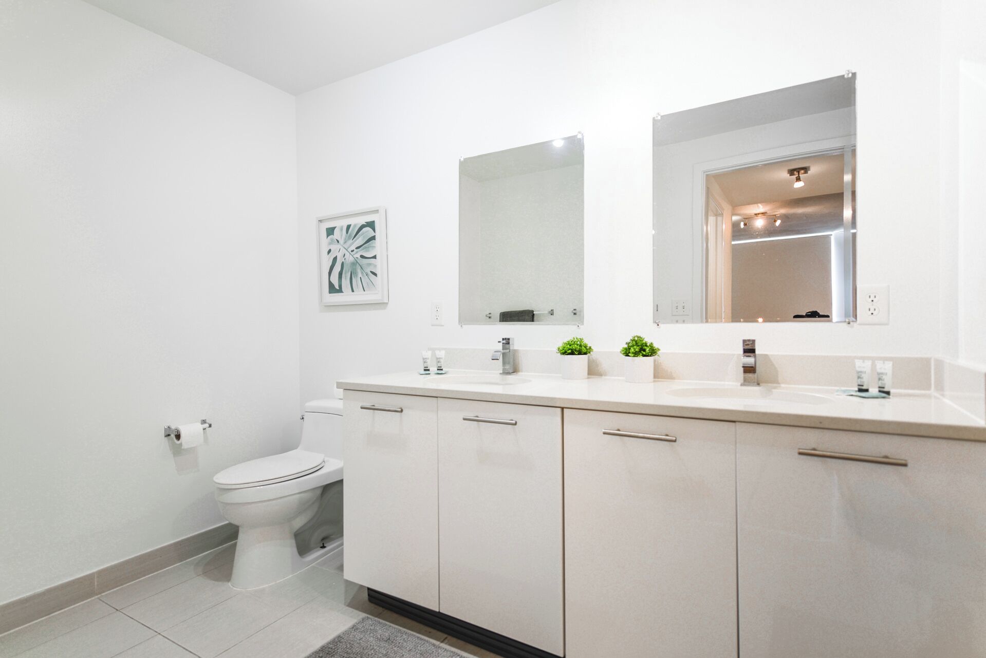 A modern bathroom with a toilet, a sink with a mirror above it, and a cabinet with drawers.