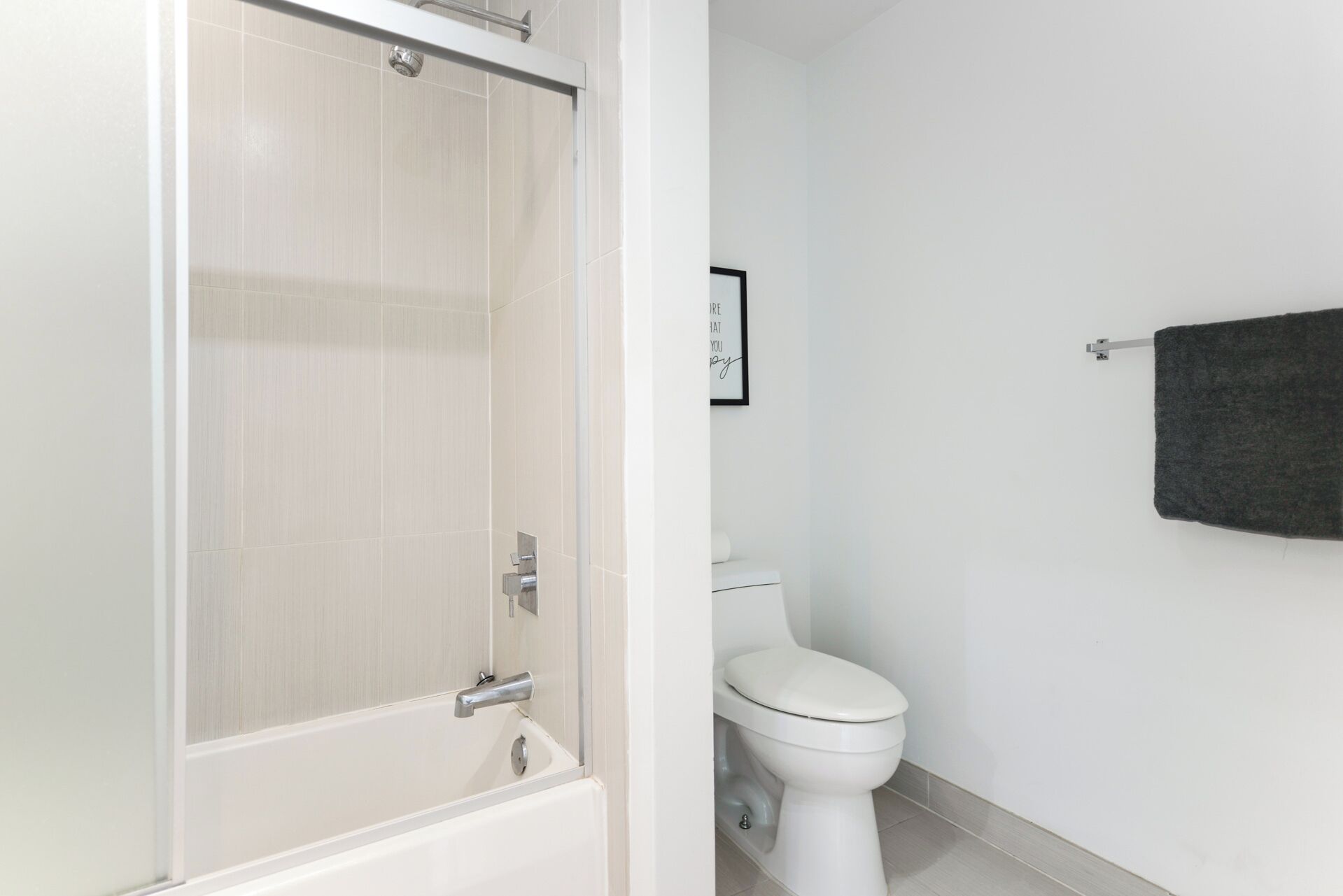 A bathroom with a white bathtub, a toilet, and a towel rack.