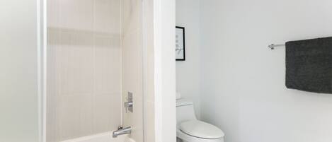 A bathroom with a white bathtub, a toilet, and a towel rack.
