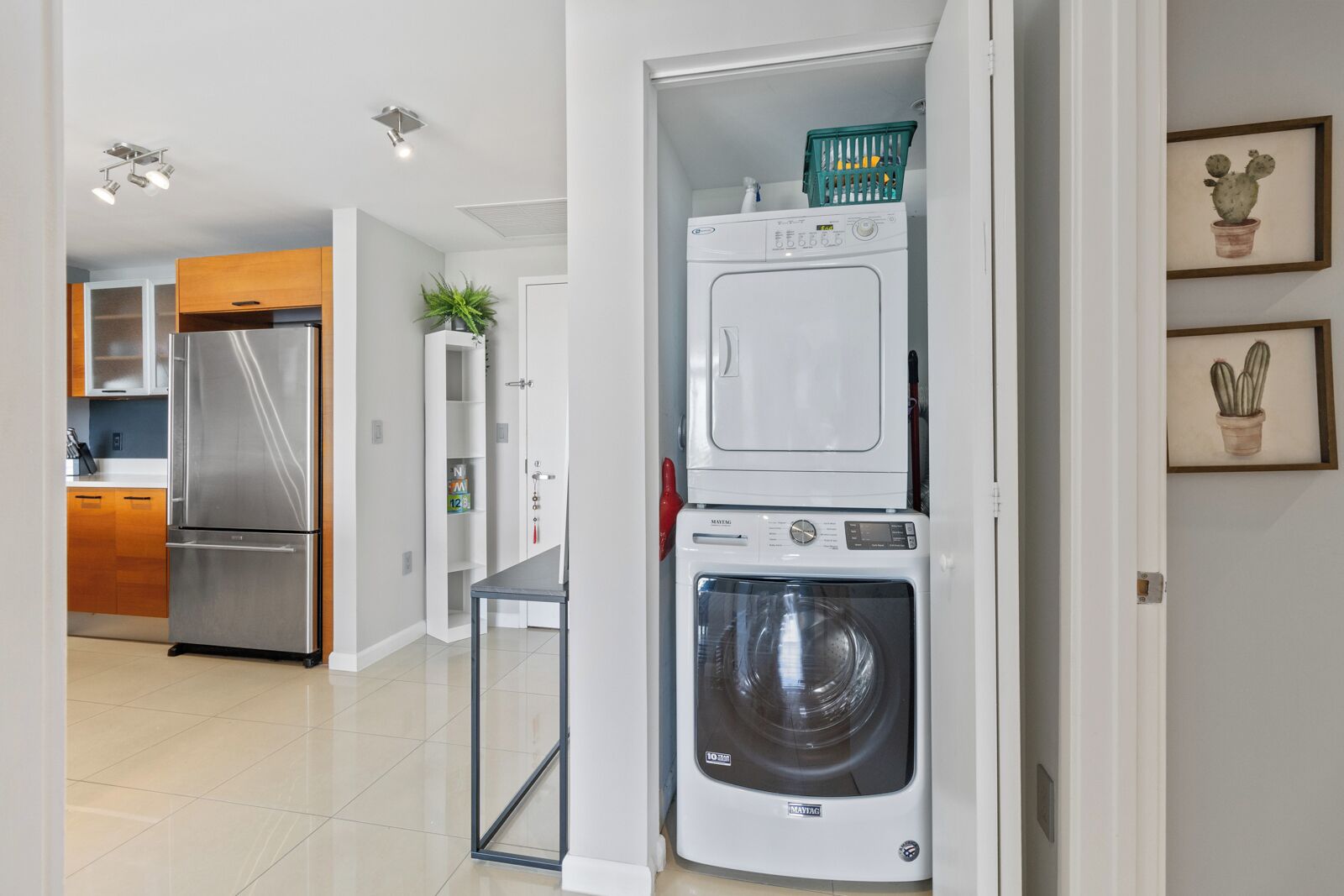 A laundry area with stacked appliances, a refrigerator, and a washing machine.