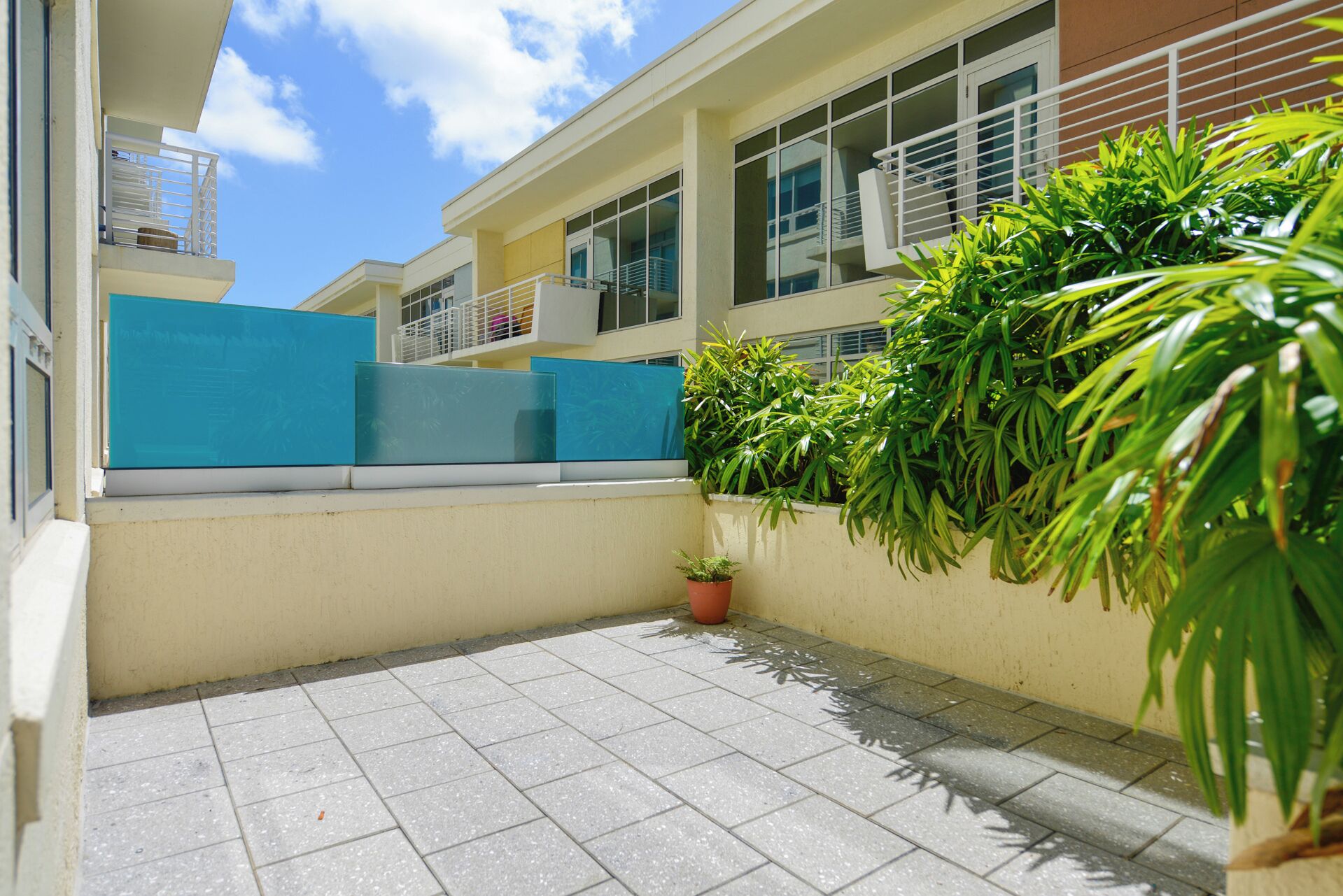 A clean, tiled patio area with a small potted plant and a blue screen.