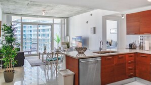 Une cuisine moderne dotée d’un grand îlot central, de meubles en bois et offrant une vue sur un immeuble de grande hauteur.